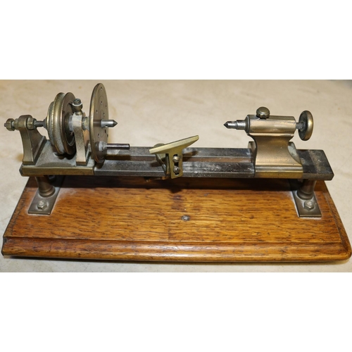 46 - A small brass model of a basic wood turning lathe. Mounted on a hardwood plinth. Intended to be a st... 