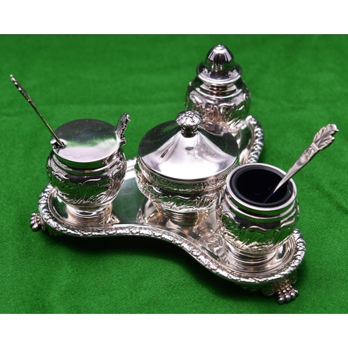 27 - A decorative silver 4-piece condiment set. On a triangular stand raised on 3 feet with blue glass in... 