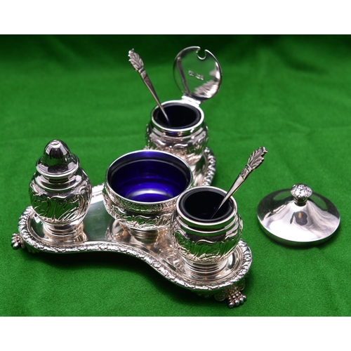 27 - A decorative silver 4-piece condiment set. On a triangular stand raised on 3 feet with blue glass in... 