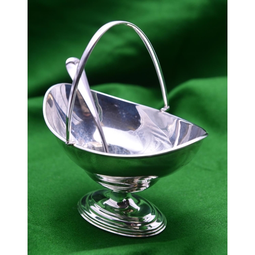 29 - A silver sugar bowl and pierced spoon. A plain oval bowl with hinged handle. Hallmarked London 1904,... 