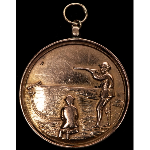 139 - A 9 ct gold shooting award, obverse shooting left with clay pigeon operative kneeling at his feet, d... 