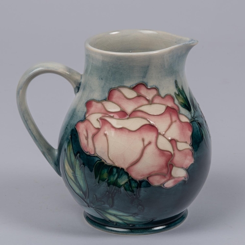 11 - A Moorcroft pottery jug with rose design. Impressed marks etc to base with arrow year cypher, AW and... 