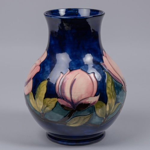 16 - A Moorcroft pottery vase. With magnolia design on a dark blue ground. Marks and sticker to base, dat... 