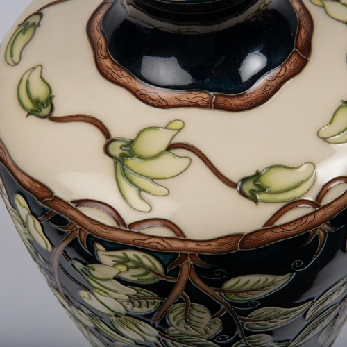 22 - A Moorcroft pottery large vase. With wisteria on a dark blue and cream ground. Marks to base, signed... 