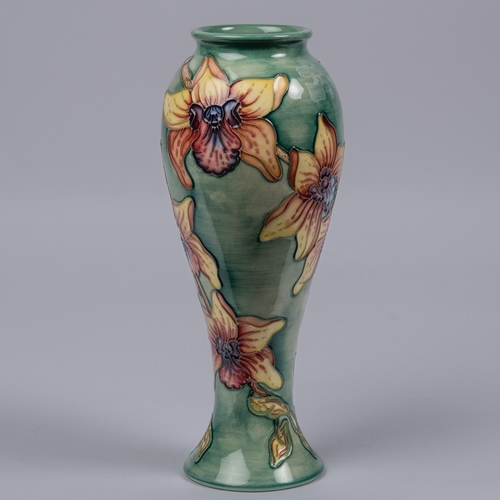 23 - A Moorcroft pottery tall vase. With iris type flowers on green ground. Marks to base, MP, HC date cy... 