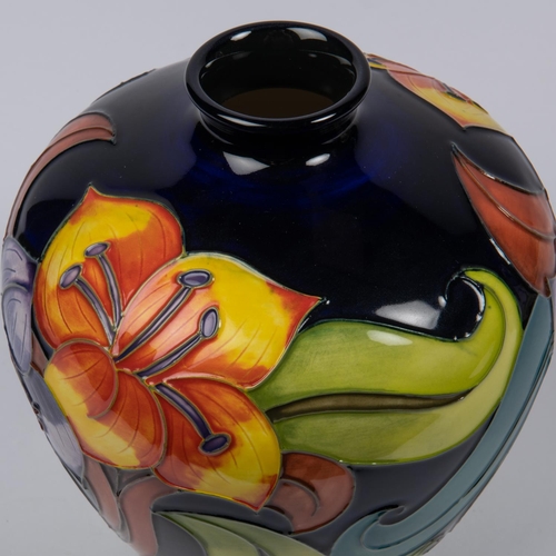 24 - A Moorcroft pottery vase. With lilies on dark blue ground. Marks to base, DJS, racquet date cypher f... 