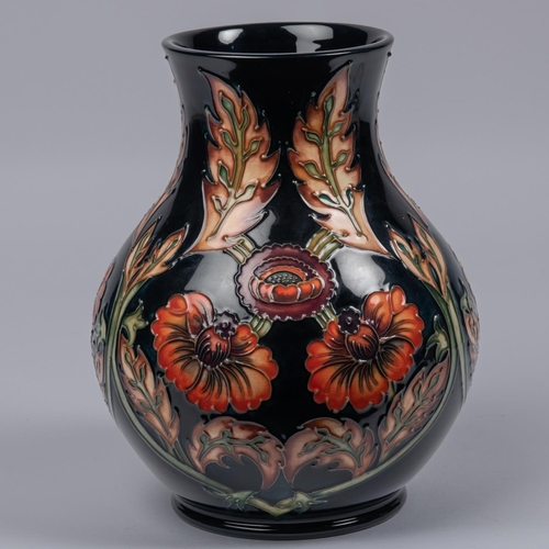 26 - A Moorcroft pottery vase. With orange flowers on dark blue ground. Marks to base, MH, GP, gate date ... 