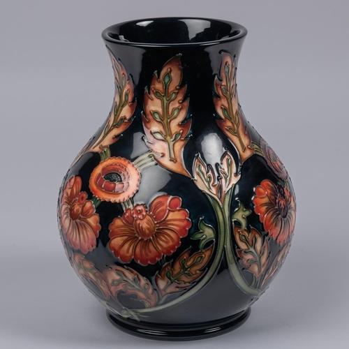 26 - A Moorcroft pottery vase. With orange flowers on dark blue ground. Marks to base, MH, GP, gate date ... 