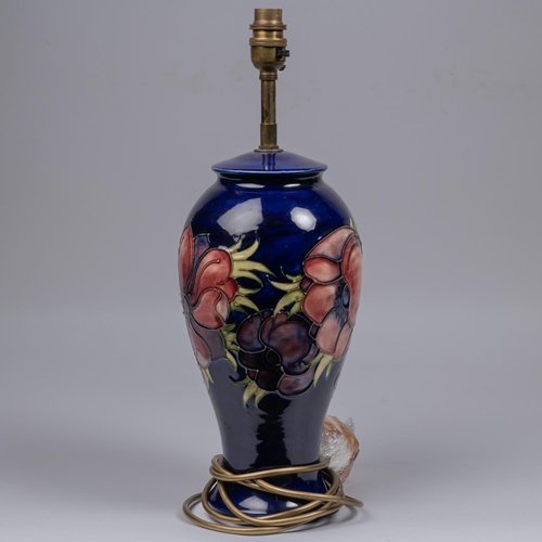 34 - A Moorcroft pottery lamp vase. With anemone design on dark blue ground. Marks to base, MH. H.435mm. ... 