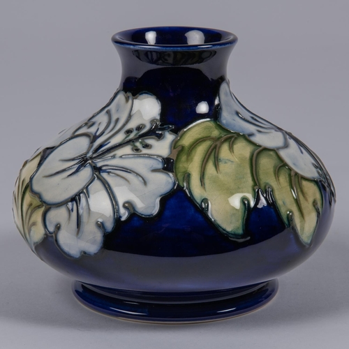 35 - A Moorcroft pottery vase. Earlier floral design by Walter Moorcroft on a dark blue ground. Impressed... 