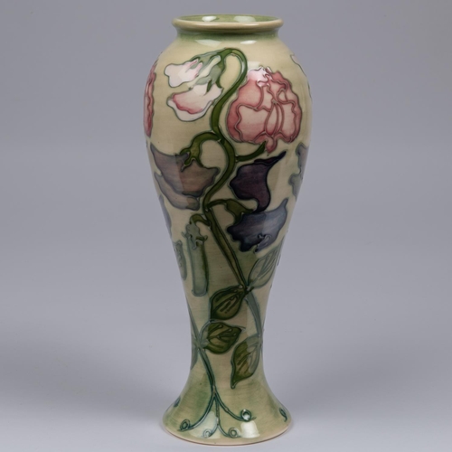 38 - A Moorcroft pottery tall vase. With sweet peas on a light graded green base. Impressed marks to base... 