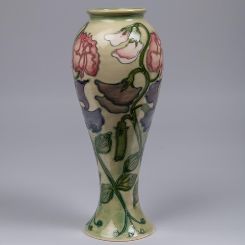 38 - A Moorcroft pottery tall vase. With sweet peas on a light graded green base. Impressed marks to base... 