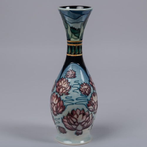 40 - A Moorcroft pottery slim vase. Water liles in a landscape on a graded blue ground. Impressed marks t... 