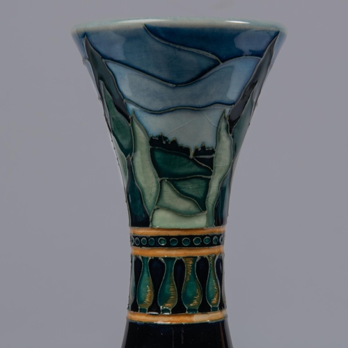 40 - A Moorcroft pottery slim vase. Water liles in a landscape on a graded blue ground. Impressed marks t... 