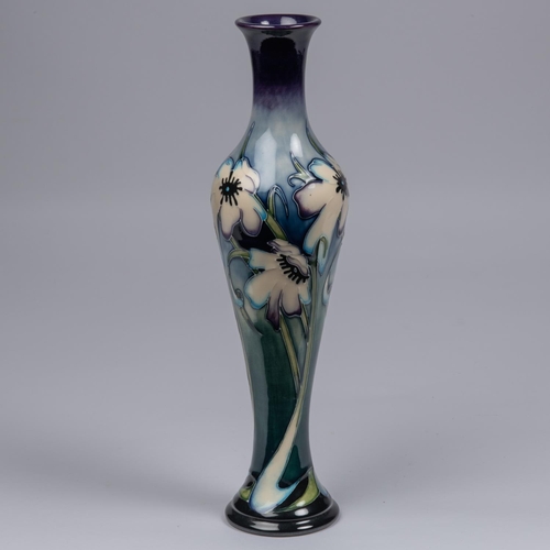 56 - A Moorcroft pottery slim vase. Blue tinged white flowers on a graded green and blue ground. Marks to... 