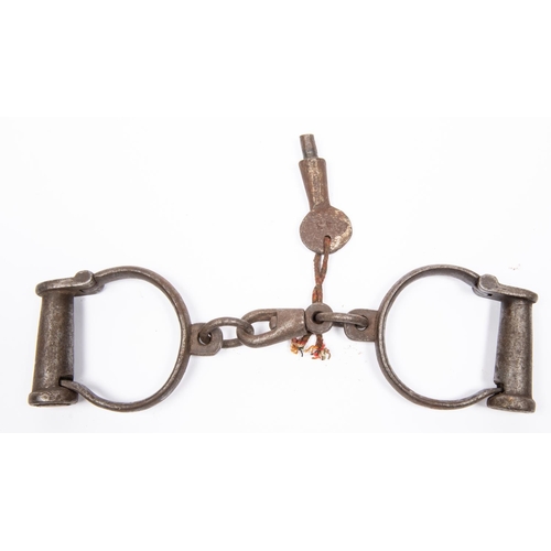 54 - A pair of old iron plug lock handcuffs, one numbered 