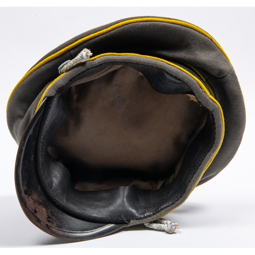 161 - A well made copy of a Third Reich cavalry officer's peaked cap, grey with yellow piping, alloy badge... 