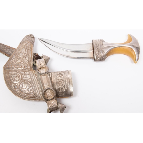 447 - An Arab jambiya with scabbard, embellished with silvered braid and white metal, on its braided belt.... 