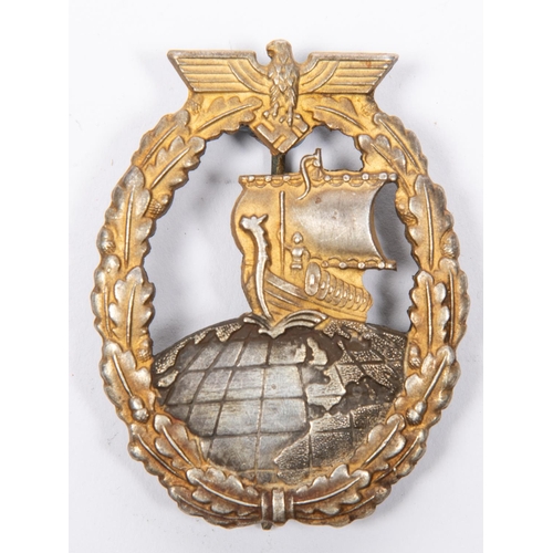 121 - A Third Reich Auxiliary Cruiser War badge, with grey globe, gilt ship and wreath, and flat grey reve... 