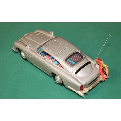 101 - James Bond tinplate Aston Martin toy by Gilbert of  America. Battery operated mechanism operates fla... 