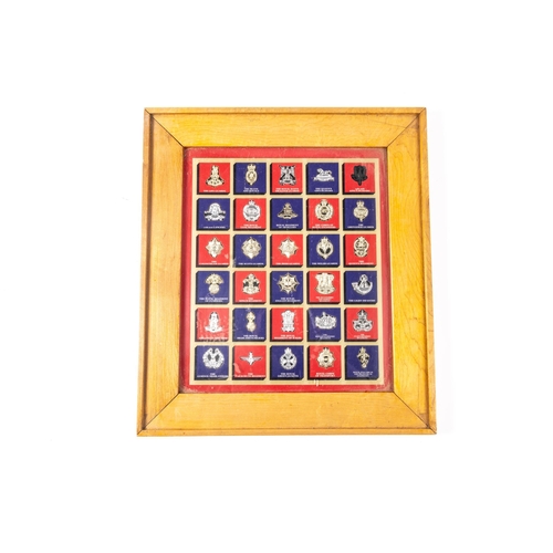 267 - A framed display of badges of the Queen's (Ryl West Surrey Regt), including ERII bandsman's helmet p... 