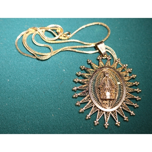 41 - An 18K gold  hallmarked chain with a large filigree sunburst style pendant with a small building to ... 