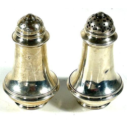 30 - Two silver peppers on pedestal feet. London 1910, marks rubbed. Weight 84gms.