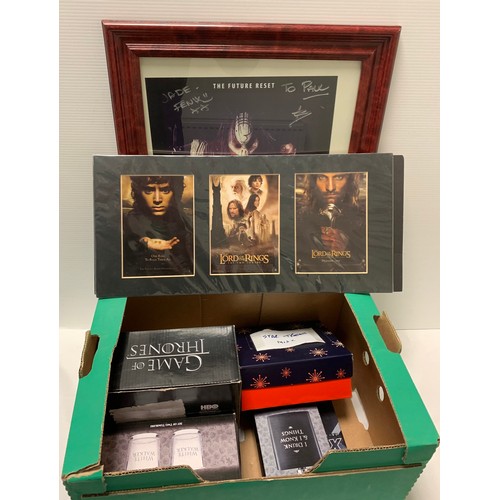 134 - A Box of TV / Film Memorabilia 
Signed photographs, posters, glasses, games etc with a box of DVD / ... 