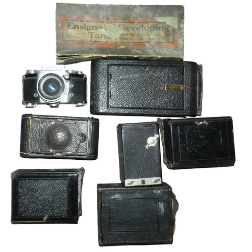 25 - Box of defective cameras, lens hoods, flash units and a 1901 developing tank in box.