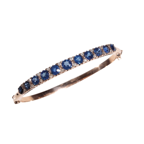 199 - A SAPPHIRE AND DIAMOND BANGLE the eleven graduated  cushion-cut sapphires interspersed with round-cu... 