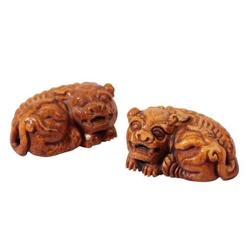 71 - A PAIR OF CHINESE CARVED HORN LIONS, each reclining beast with finely detailed musculature and bushy... 