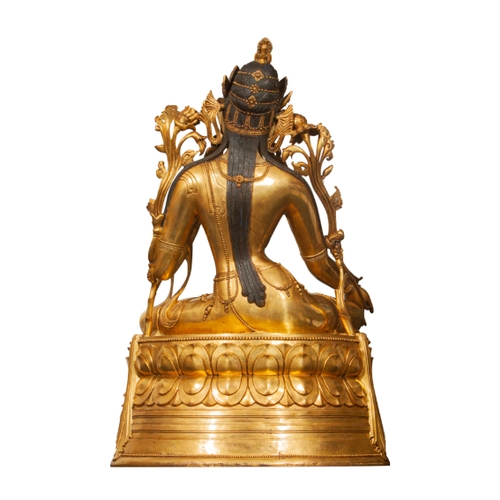 81 - A MONUMENTAL SINO-TIBETAN GILT BRONZE OF TARA, QING wearing an elaborate headdress and seated on a l... 
