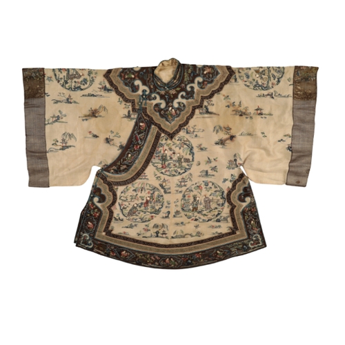 87 - A CHINESE IVORY SILK SHORT ROBE embroidered with figures in roundels and landscape vignettes within ... 