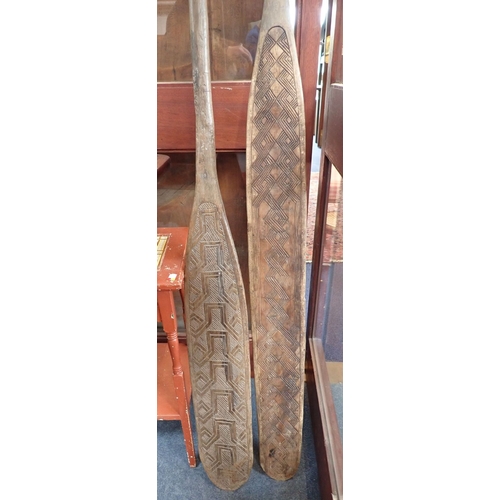 37 - TWO INDONESIAN DECORATIVE WOODEN PADDLES 218cm and 226cm long