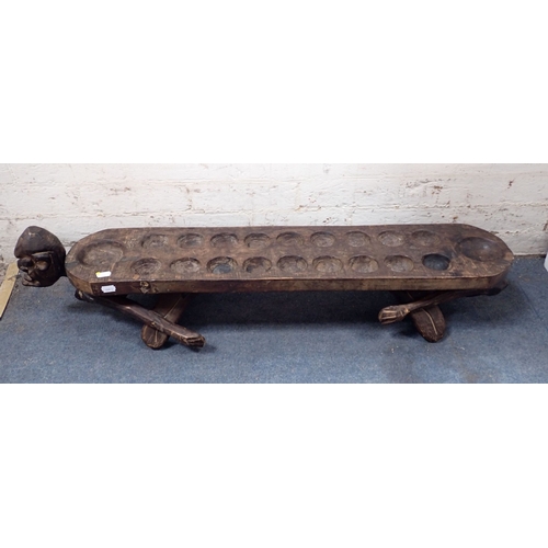 333 - AN AFRICAN TRIBAL MANCALA GAME BOARD 102cm long (one head and a hand missing)