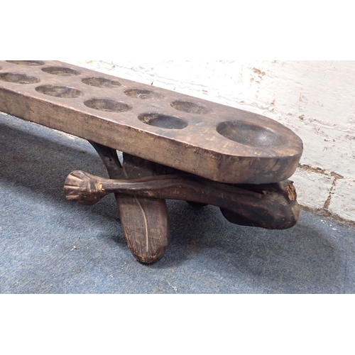 333 - AN AFRICAN TRIBAL MANCALA GAME BOARD 102cm long (one head and a hand missing)