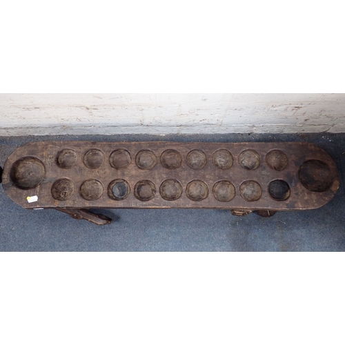 333 - AN AFRICAN TRIBAL MANCALA GAME BOARD 102cm long (one head and a hand missing)