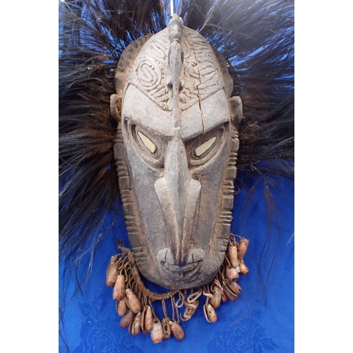 136 - A TRIBAL WOODEN MASK Papua New Guinea, inlaid shell eyes, shell fringe beard and cassawary feather d... 