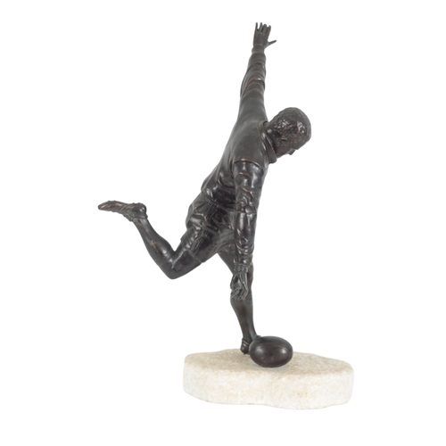 121 - A LARGE BRONZE MODEL OF A RUGBY PLAYER in kicking pose, standing on a rough-hewn marble base, 51cm h... 