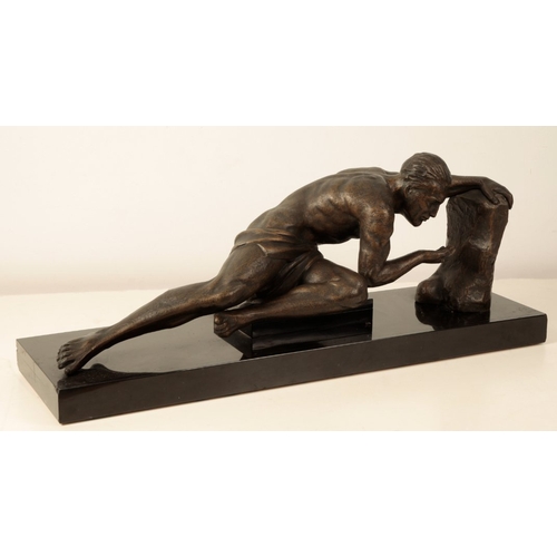 142 - A BRONZE-EFFECT ART DECO STYLE SCULPTURE modelled as a male in recumbent pose with his left arm rest... 