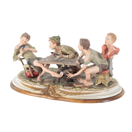 306 - A CAPODIMONTE FIGURE - 'THE CARD CHEATS' modelled by Merli, on wooden plinth, 30cm high x 56cm wide ... 