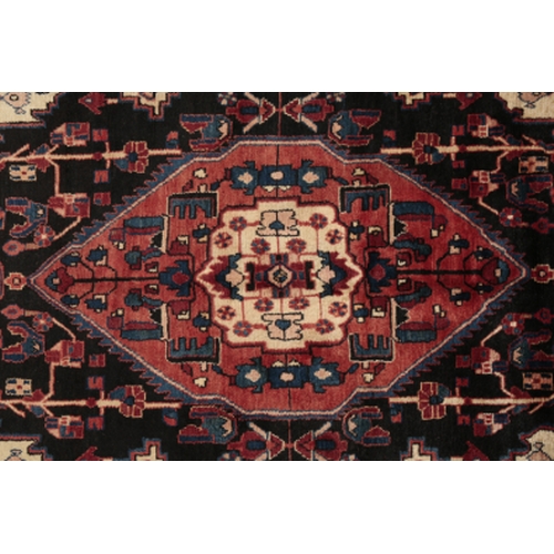 189 - A NORTH WEST PERSIAN NAHAWAND CARPET woven in blue, tan and red with double headed lozenge medallion... 