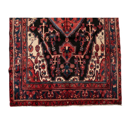 189 - A NORTH WEST PERSIAN NAHAWAND CARPET woven in blue, tan and red with double headed lozenge medallion... 