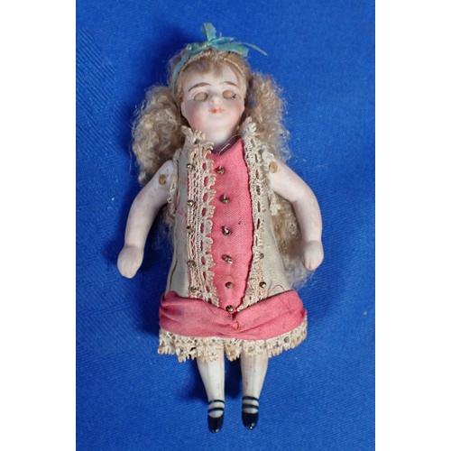 135 - A JOINTED BISQUE DOLL WITH MOVING EYES and original clothing, 10cm high