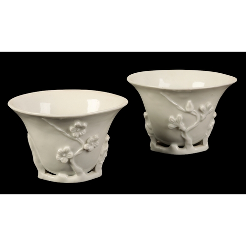 106 - A PAIR OF CHINESE BLANC DE CHINE LIBATION CUPS Qing, modelled in relief with prunus, on branch bases... 