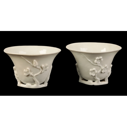 106 - A PAIR OF CHINESE BLANC DE CHINE LIBATION CUPS Qing, modelled in relief with prunus, on branch bases... 