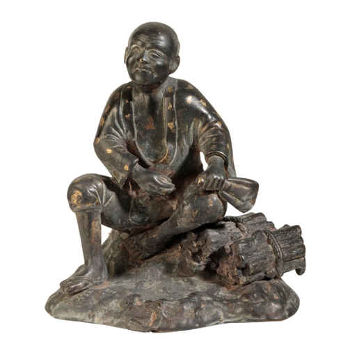 120 - A JAPANESE BRONZE FIGURE OF A MAN Meiji, seated on a rock beside a pile of wood, some gold splashing... 