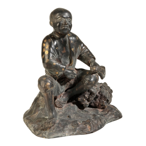 120 - A JAPANESE BRONZE FIGURE OF A MAN Meiji, seated on a rock beside a pile of wood, some gold splashing... 