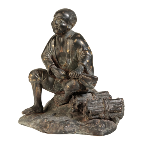 120 - A JAPANESE BRONZE FIGURE OF A MAN Meiji, seated on a rock beside a pile of wood, some gold splashing... 