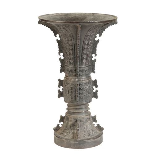 19 - A CHINESE BRONZE GU-SHAPED BEAKER VASE in the archaistic style, cast with flanges and geometric desi... 